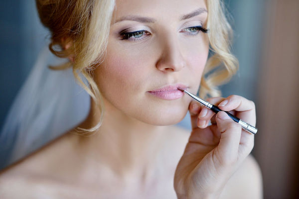 bride putting on lipstick - wedding makeup - wedding day - wedding day touchups