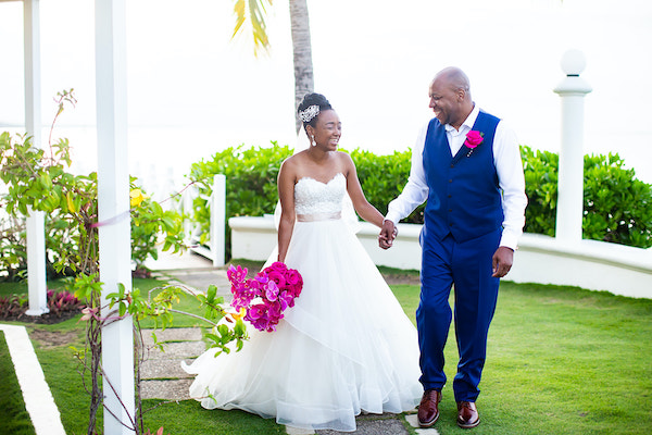 North Carolina destination wedding planner- Jamaican destination wedding - Moon Palace Jamaica- just married - bride and groom walking hand in hand - hot pink bridal bouquet