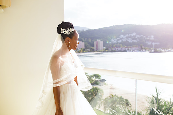 North Carolina destination wedding planner- Jamaican destination wedding - bride ion balcony overlooking beach - bride in ballgown