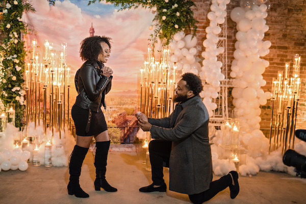 Durham man down on one knee proposing in front of a Paris themed backdrop